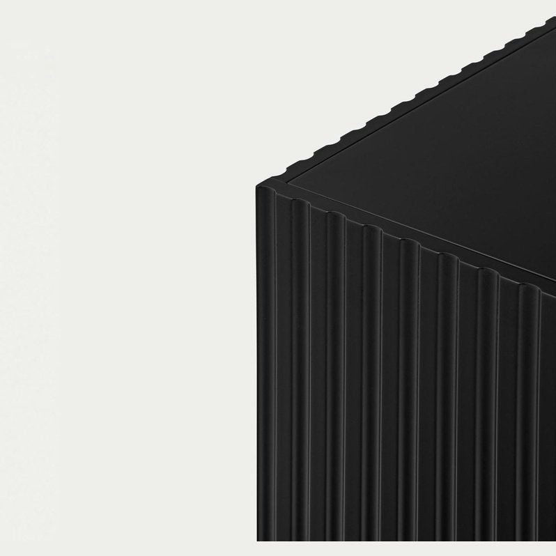 Primer plano de una esquina acanalada negra del armario Doric 2P2C de MDF con 2 puertas y 2 cajones sobre un fondo claro, que encarna un diseño minimalista.