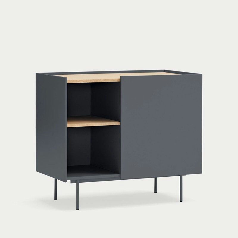 La Cómoda en MDF y Roble con 3 Cajones y Puerta Otto 1P3C es un mueble moderno y minimalista con un exterior en color gris oscuro, que cuenta con estantes abiertos a la izquierda y un compartimento cerrado a la derecha. Su superficie e interior de madera clara combinan versatilidad y estilo a la perfección con cualquier espacio.