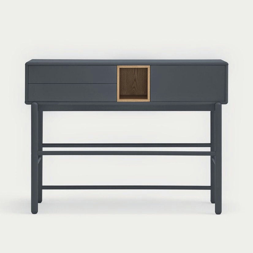 La Consola Corvo 1P2C es una consola de color gris oscuro con dos cajones y un compartimento central. Presenta líneas limpias y minimalistas y se apoya sobre cuatro patas rectas, ofreciendo soluciones de almacenamiento con estilo gracias a su diseño elegante y funcional.