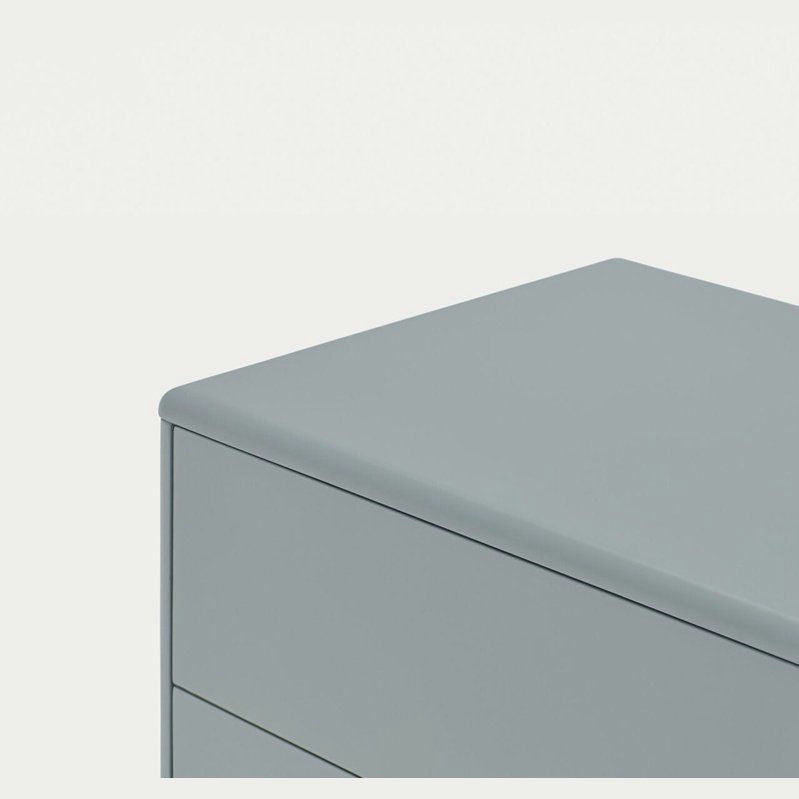 Primer plano de la esquina superior de la Consola Corvo 1P2C gris claro con líneas elegantes y superficies lisas. Esta pieza minimalista encarna un diseño elegante y funcional, lo que la convierte en una solución de almacenamiento estilizada ideal para cualquier espacio moderno.