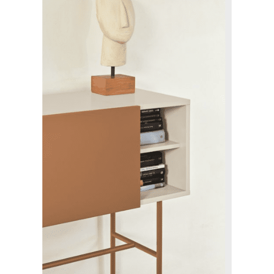 La Consola Nube 1P2C cuenta con una puerta corrediza de color tostado que se abre hacia estantes llenos de libros y está coronada por una escultura abstracta sobre una base de madera, que encarna el diseño minimalista moderno.