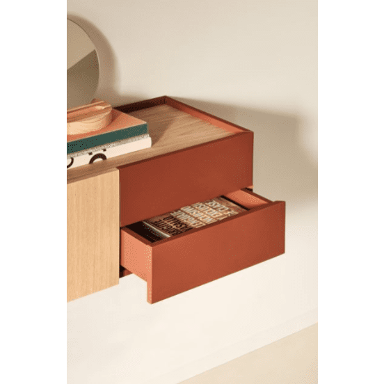 La Consola Otto 2P2C (Suspendida) es una estantería de madera que combina modernidad y funcionalidad, con dos cajones abiertos, uno de color madera y otro de color marrón rojizo, para libros y una agenda. Un espejo redondo encima con libros adicionales resalta su diseño elegante y práctico.