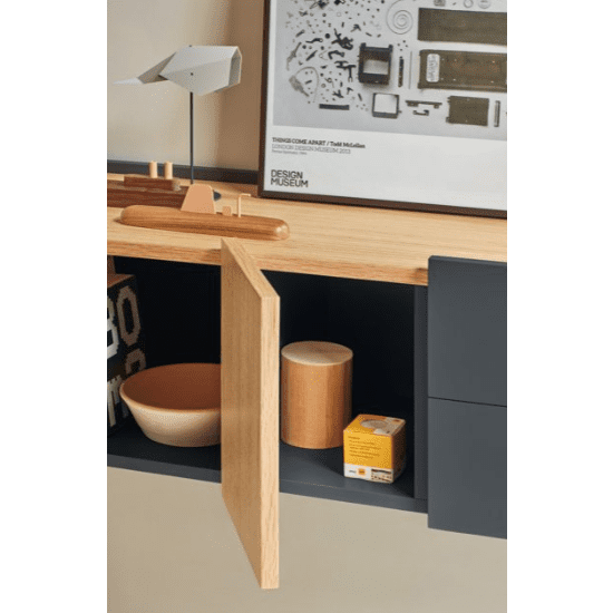 La puerta abierta del armario de madera revela un cuenco beige, un recipiente cilíndrico y una pequeña caja, que encarnan la modernidad y la funcionalidad. Sobre la elegante Consola Otto 2P2C (Suspendida) hay una lámpara moderna junto a un póster enmarcado en la pared.