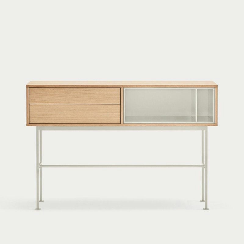 La Consola Yoko 2C es una llamativa pieza de diseño contemporáneo que ofrece almacenamiento moderno con un elegante acabado en madera y patas de metal. Cuenta con dos amplios cajones a la izquierda y una elegante sección de vidrio a la derecha.