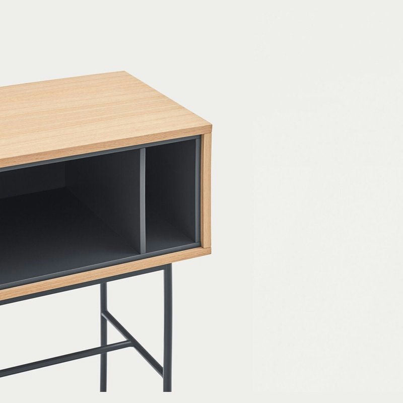 La Consola Yoko 2C combina madera y metal, presentando un estante abierto y dos compartimentos para un almacenamiento moderno, sobre un fondo sencillo.