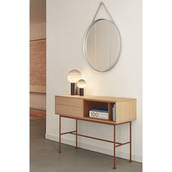 La Consola Yoko 2C, una mesa consola de madera con elegantes patas de metal, está acompañada por dos lámparas de globo y un libro debajo de un espejo de pared circular. Los interiores de la habitación en colores neutros resaltan una decoración minimalista combinada con un espacio de almacenamiento moderno y un diseño contemporáneo.