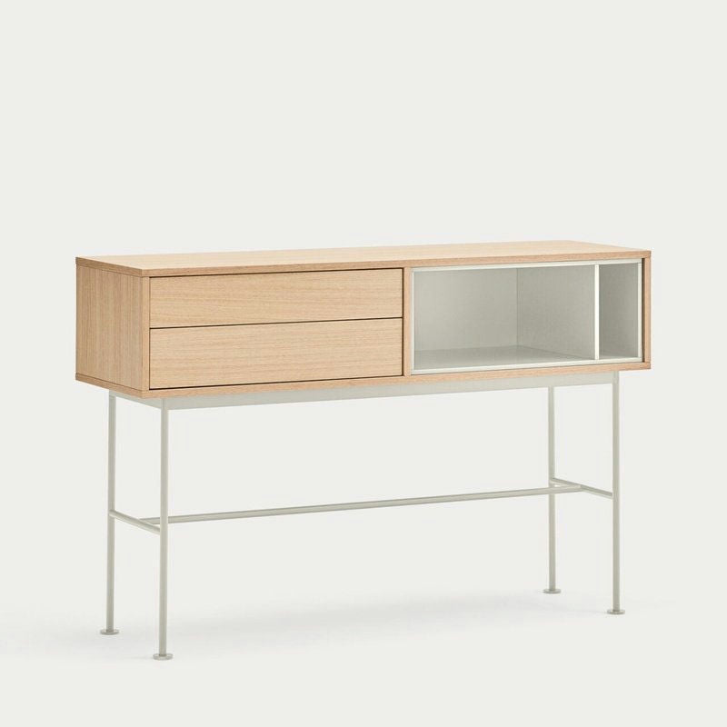 El aparador minimalista Consola Yoko 2C de madera clara cuenta con dos cajones, un estante abierto y patas delgadas de metal blanco. Su diseño contemporáneo combina a la perfección con cualquier fondo liso y ofrece un almacenamiento moderno y elegante.