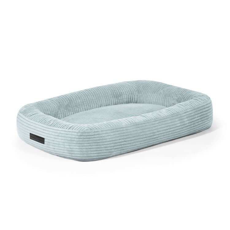 Cama rectangular para perro de pana azul claro con laterales elevados y base plana acolchada, inspirada en el diseño DOG BED 75 WAVES. Medidas: 75×60×18 cm. Hipoalergénica.