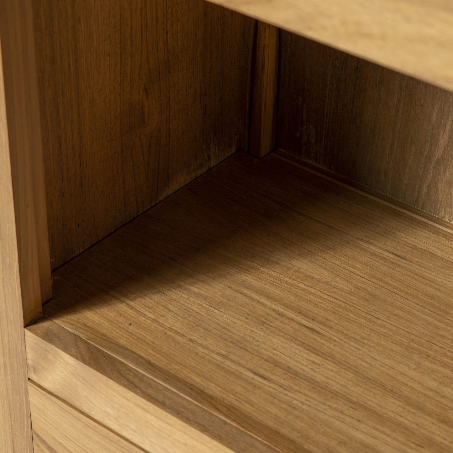 Primer plano del estante vacío de Estantería en Madera Teca Begur, que muestra su diseño contemporáneo, veta de madera de teca visible y sombra en las esquinas.