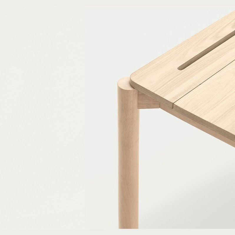 El primer plano del Escritorio de Madera Atlas muestra un acabado suave y contemporáneo con una pata vertical y una pequeña ranura en la esquina de la mesa.