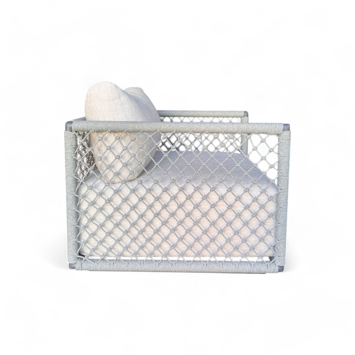 El Sillón de exterior de aluminio y cuerda gris OCEAN (80×83×62 cm) presenta un diseño moderno con laterales de malla, cojín impermeable de color beige claro y almohada, mostrado de perfil sobre fondo blanco.