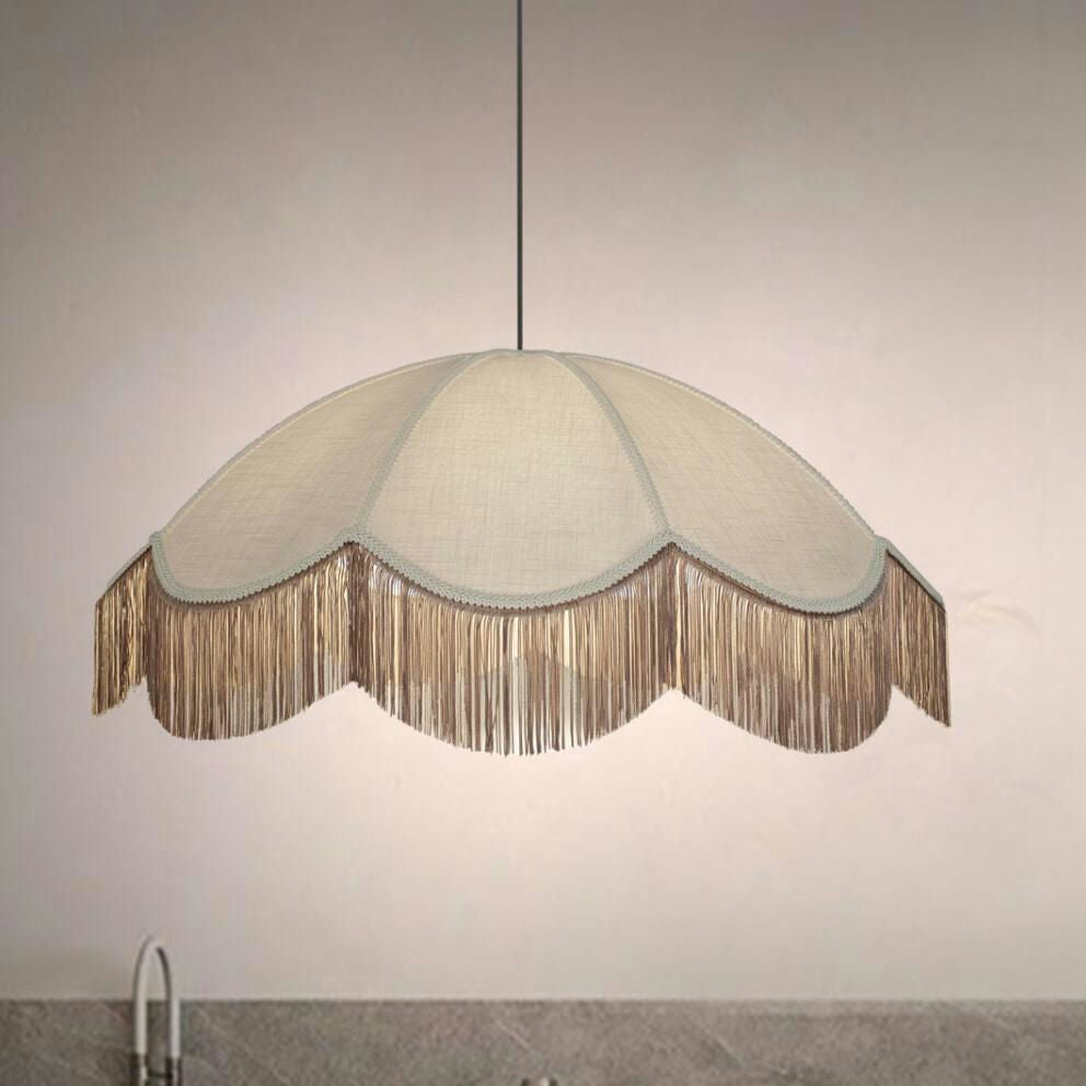 Una Lámpara de Techo Colgante Vintage Crema 30162 de color beige, festoneada y con flecos, cuelga sobre una superficie gris y proyecta un brillo cálido.