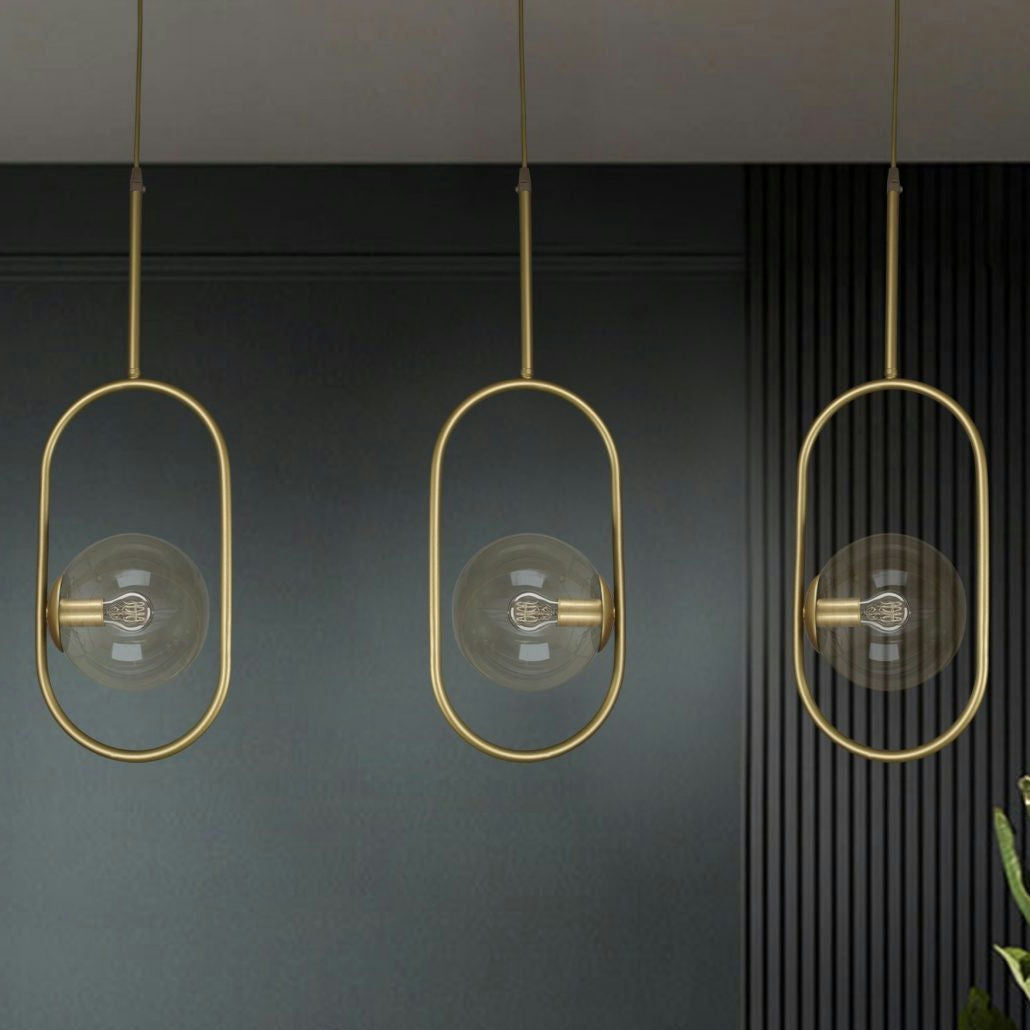 La Lámpara de Techo Colgante Moderna Dorada 3135-1C-16-3 con sus marcos ovalados y bombillas expuestas cuelga de una pared con textura oscura, incorporando un diseño industrial elegante.