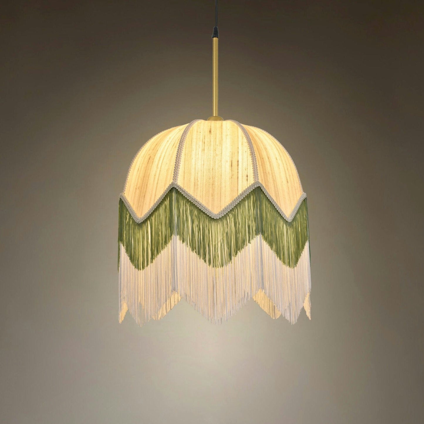 La Lámpara de Techo Colgante Vintage de Flecos 30148, con su pantalla decorativa con flecos en beige y verde, evoca el estilo Art Déco y ofrece una iluminación suave y difusa sobre un fondo liso.