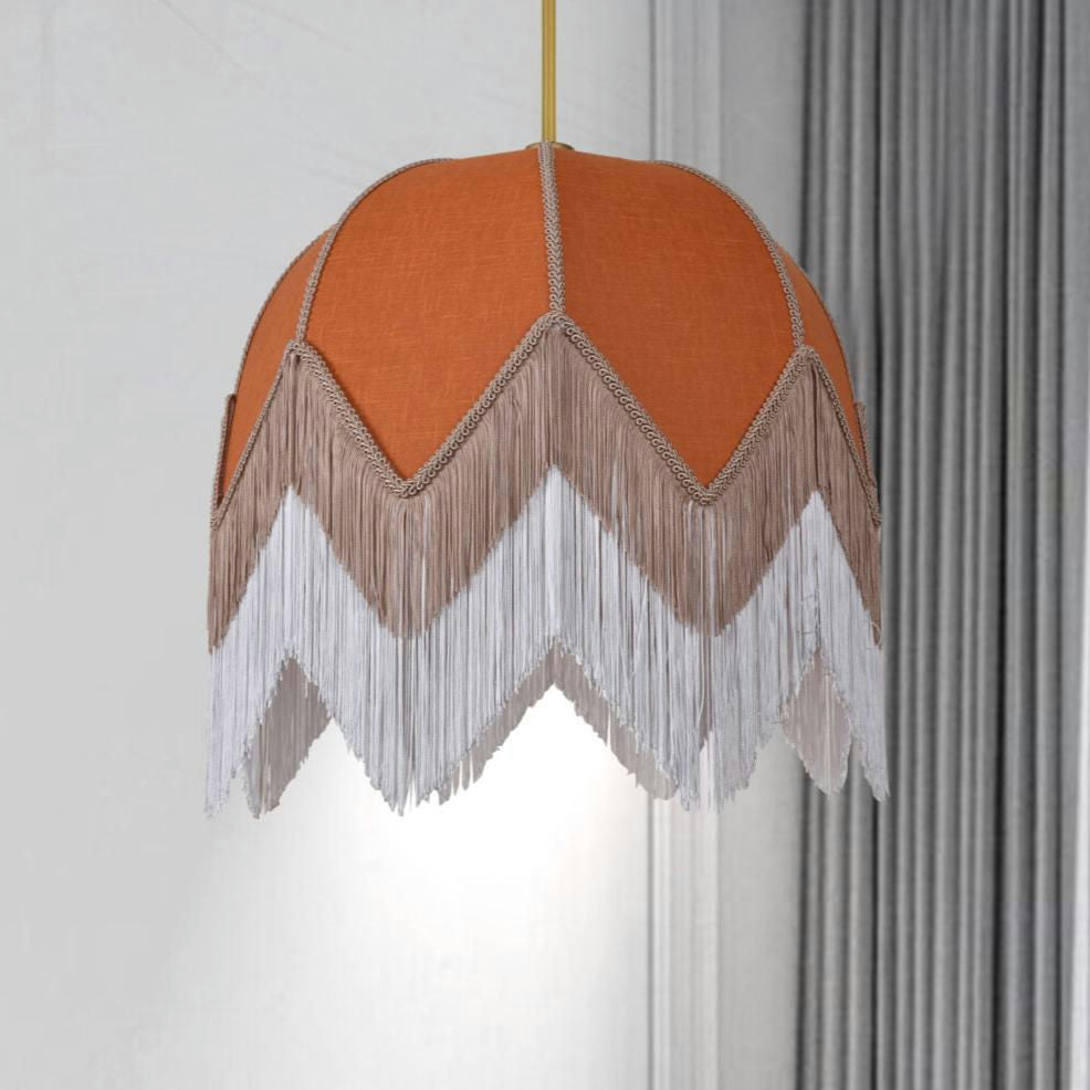 La Lámpara de Techo Colgante Vintage de Flecos Terracota 30160, con sus flecos en zigzag en color naranja y blanco, introduce un toque de diseño bohemio a la estancia, combinando perfectamente con las cortinas grises.