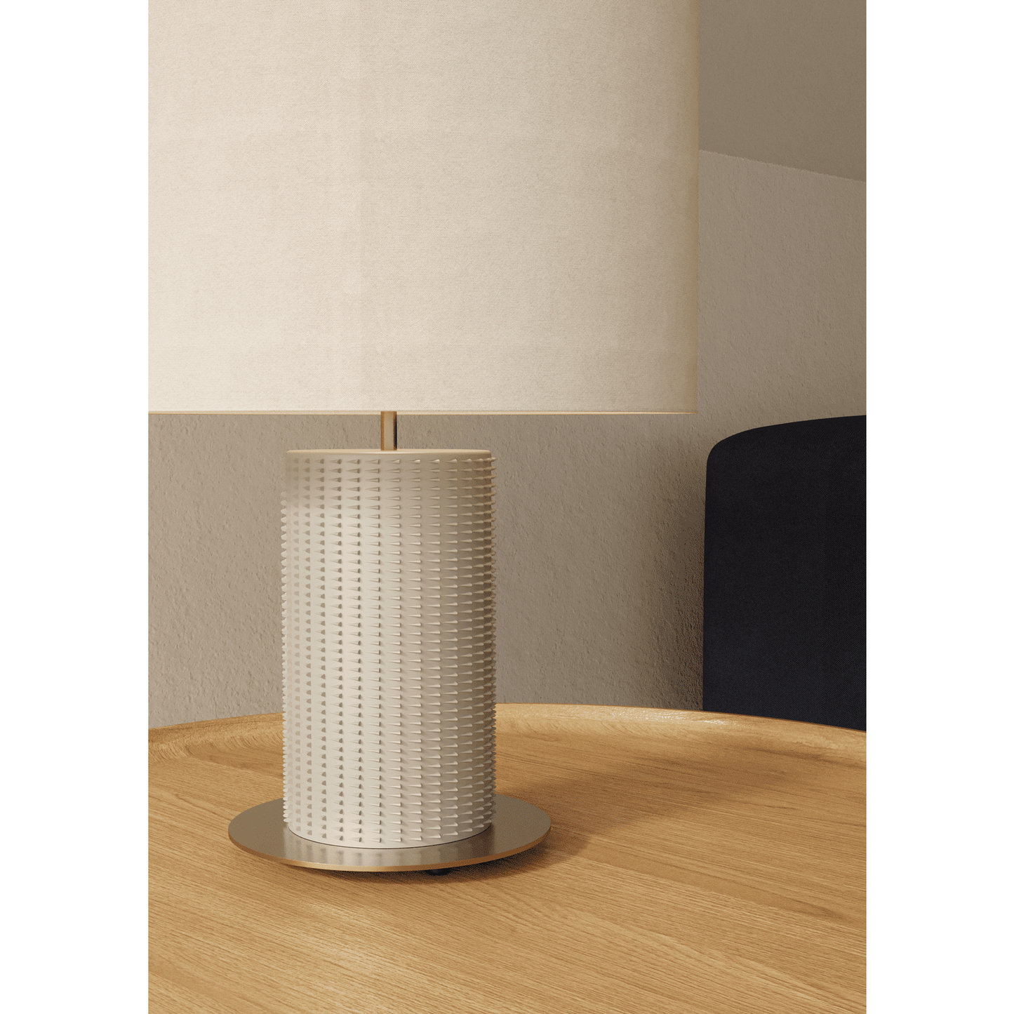 La Lámpara de mesa Dab en color beige, con base cilíndrica texturizada y pantalla redonda, reposa sobre una superficie de madera contra una pared clara, realzando el espacio con su toque decorativo moderno.