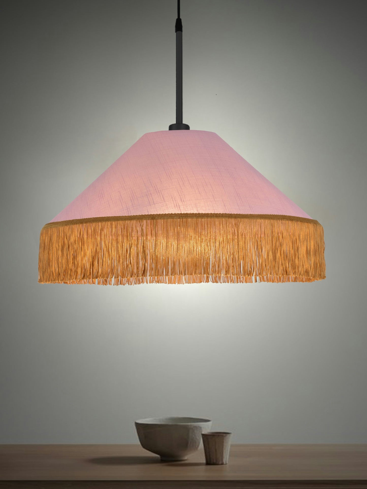 La Lámpara de techo Colgante de Flecos Dorados 30154 en rosa cuelga sobre una mesa de madera con dos cuencos de cerámica.