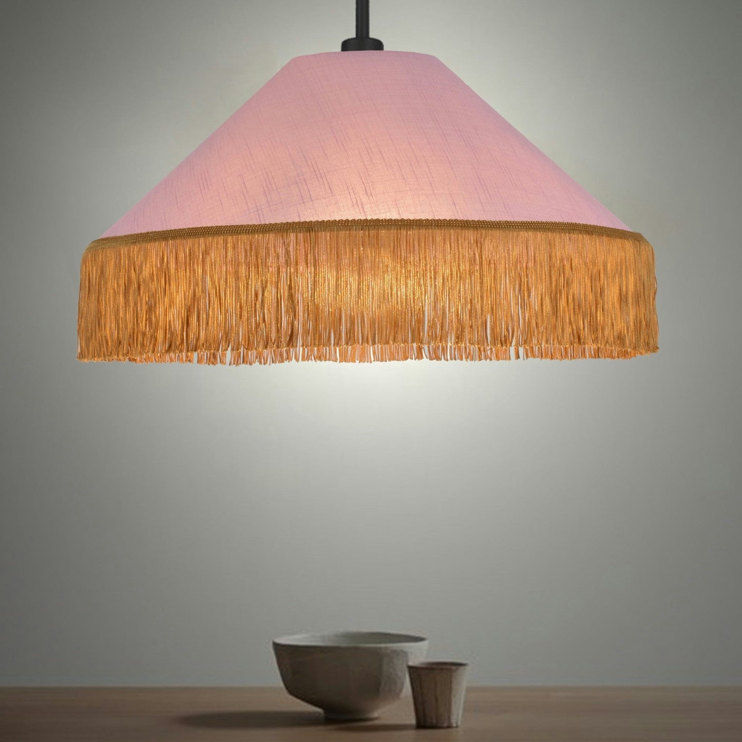 La Lámpara de techo Colgante de Flecos Dorados 30154 cuelga sobre una mesa de madera, mostrando un cuenco blanco y una taza pequeña, mezclando estilo retro y contemporáneo con sus delicados flecos dorados.