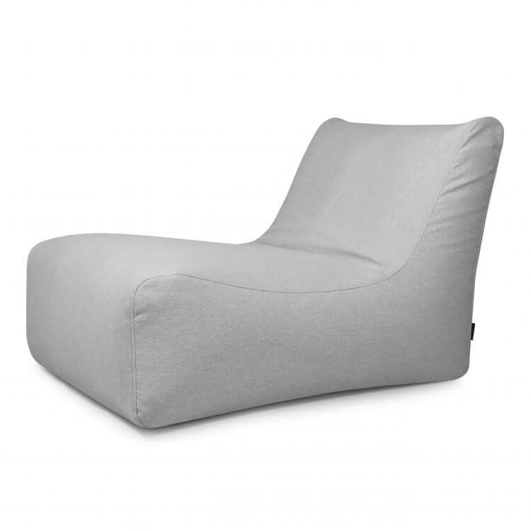 El Bean Bag Lounge 100 Dunes - uso exterior es un moderno sillón sin brazos de color gris claro con un perfil bajo y curvilíneo y un suave tapizado de tela, que ofrece un confort de alta gama similar al de un lujoso bean bag, mostrado sobre un fondo blanco.