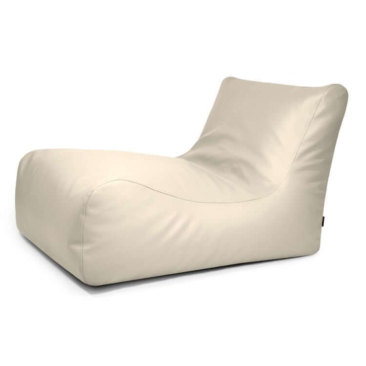 El Bean Bag Lounge 100 Outside es un moderno sillón beige sin brazos, de perfil bajo y líneas suaves y curvas. Presenta un exterior abullonado y está diseñada para su uso en exteriores, mostrada sobre un fondo blanco.