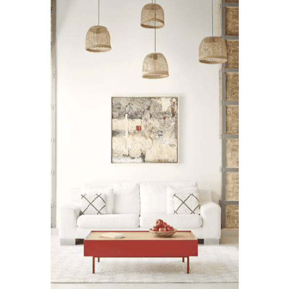 Un sofá blanco con dos cojines estampados se encuentra frente a una Mesa de Centro Arista 2C adornada con manzanas, debajo de una pintura mural. Cuatro lámparas colgantes de mimbre cuelgan del techo, aportando calidez a través de un diseño inteligente.