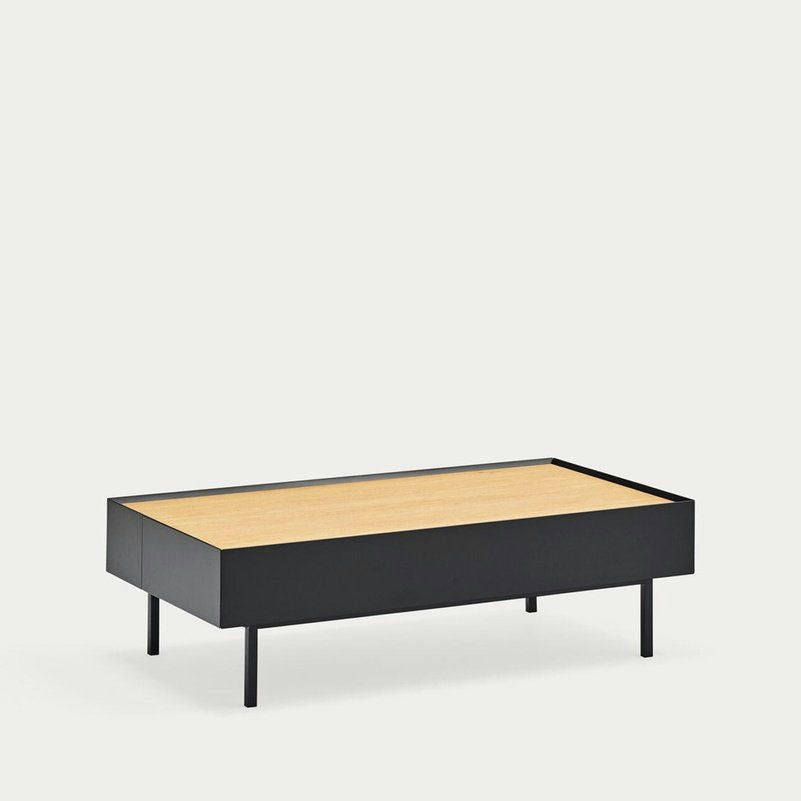La mesa de centro Arista 2C presenta un diseño rectangular moderno con una superficie de madera clara y una elegante estructura de metal negro. Sus cuatro patas rectas ofrecen un soporte resistente y un almacenamiento elegante, lo que la hace ideal para un espacio de estar con estilo.