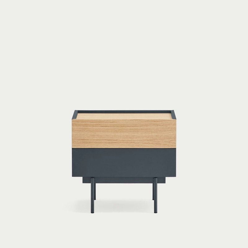 La mesita de noche Otto 2C presenta un diseño cuadrado minimalista moderno con una superficie de madera y una base de metal negro. Sostenida por cuatro patas delgadas sobre un fondo claro, es perfecta para quienes buscan estilo y almacenamiento compacto.