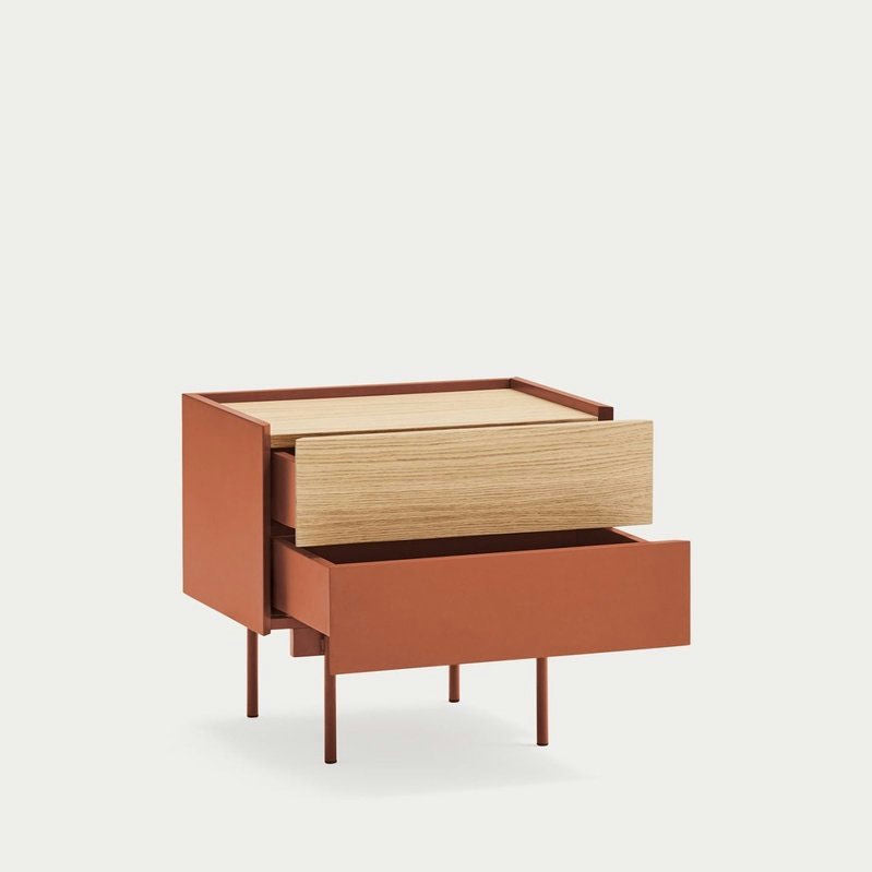 La mesita de noche Otto 2C es una mesita de noche moderna y minimalista con dos cajones, uno de madera y otro de color óxido, que ofrece un almacenamiento compacto. Se apoya sobre patas delgadas sobre un fondo liso.