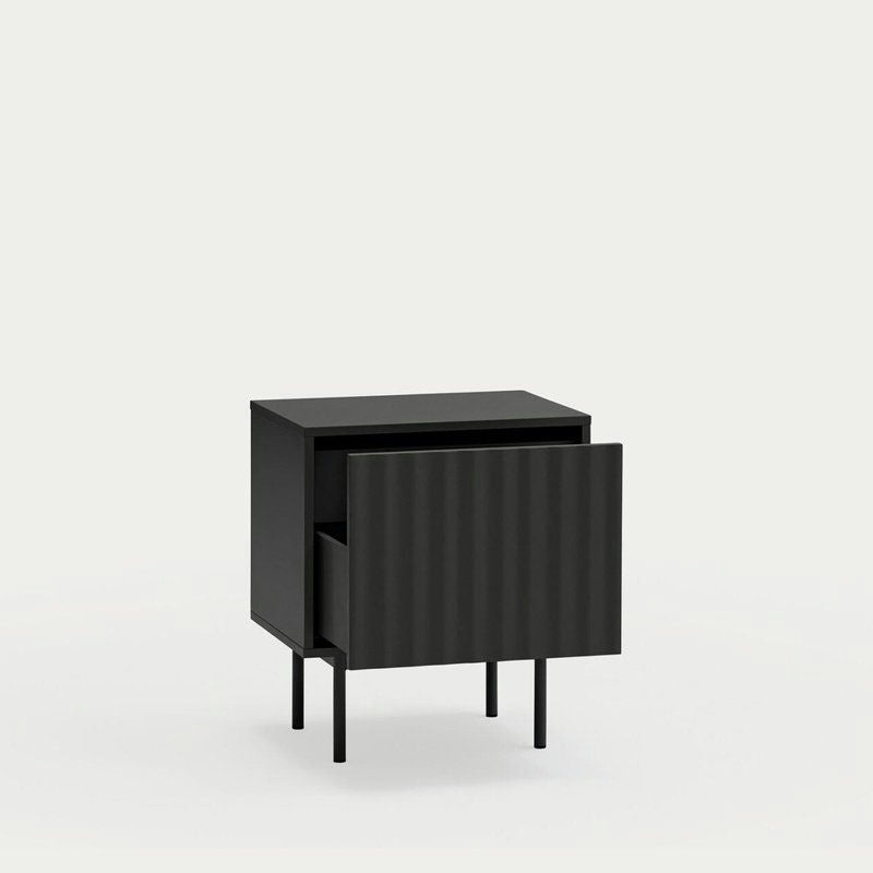 La Mesita de noche Sierra 2C, una pieza moderna en gris oscuro de Cambres Design, ofrece una elegante solución de almacenamiento con un solo cajón abierto y se apoya elegantemente sobre cuatro patas delgadas.