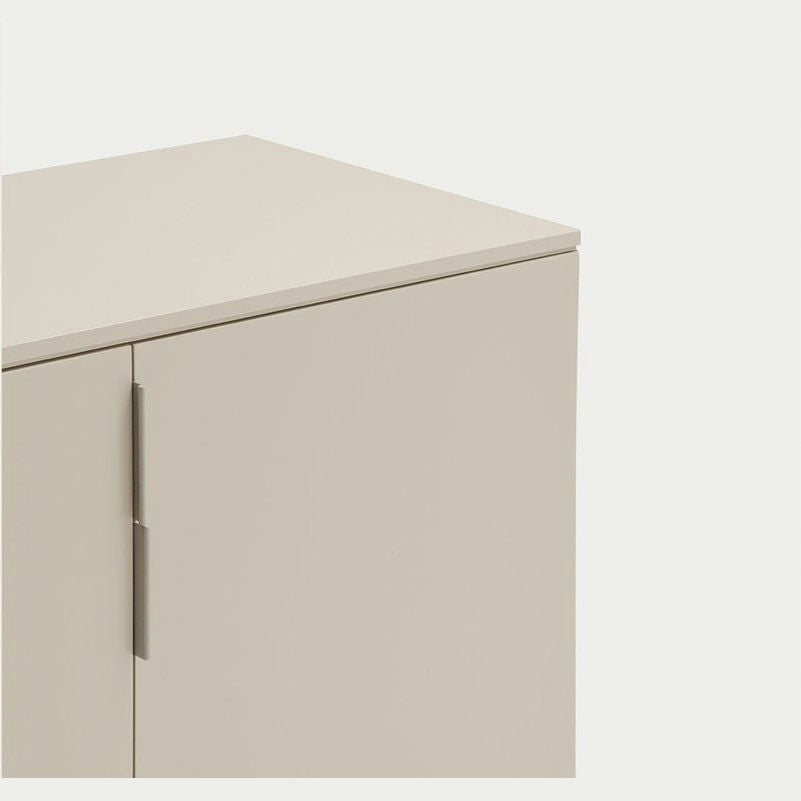 El Aparador moderno con Puertas Totem 2P presenta un acabado beige, una superficie lisa y una manija vertical, capturando el minimalismo contra un fondo blanco liso.
