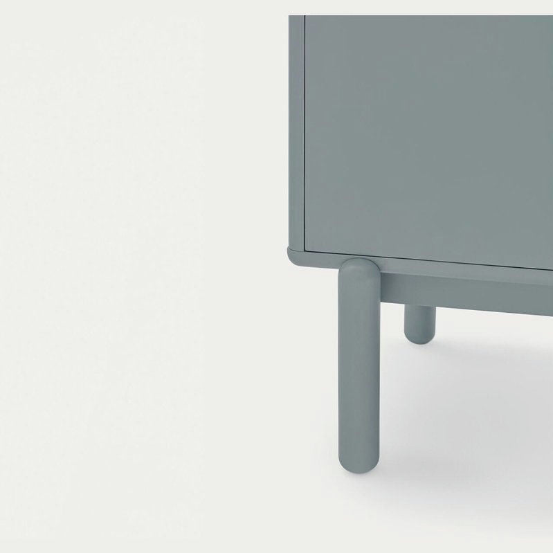 Primer plano de una esquina del Mueble Auxiliar con Puertas y Cajones Corvo 3P3C, donde se destacan sus patas cilíndricas. Esta pieza encarna la decoración contemporánea sobre un fondo claro.