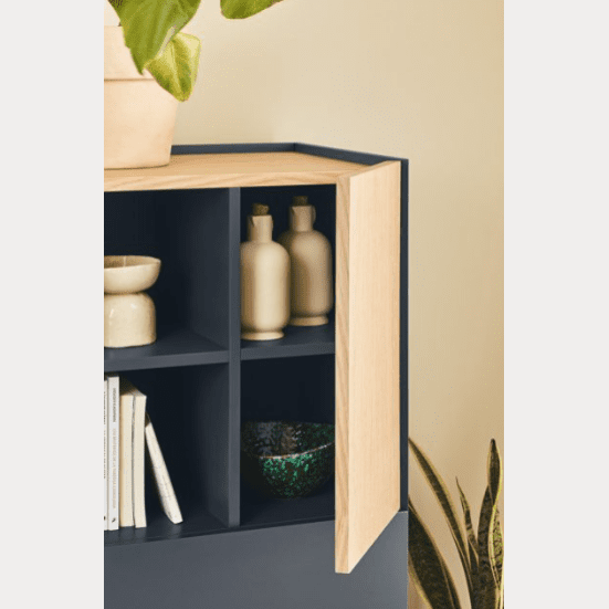 El Aparador pequeño con puertas Otto 2P2C cuenta con una estantería esquinera con cubierta de madera y un compartimento abierto en el que se exhiben jarrones, cuencos y libros. En la parte superior se ve parcialmente una planta y otra a un costado, lo que ofrece un diseño moderno que complementa cualquier espacio sin esfuerzo.