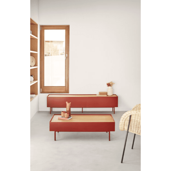 La sala de estar minimalista cuenta con una ventana de madera, paredes blancas, mesas rojas y una silla beige. El diseño moderno se destaca por el elegante Mueble TV Arista 1P2C. Los estantes brindan un almacenamiento sofisticado para la decoración, con flores secas en un pequeño jarrón sobre la mesa.