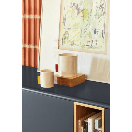 Dos tazas de cerámica Mueble TV Corvo 2P2C descansan sobre una superficie oscura con un soporte de madera, realzando bellamente el diseño contemporáneo de una obra de arte abstracta enmarcada en el fondo.
