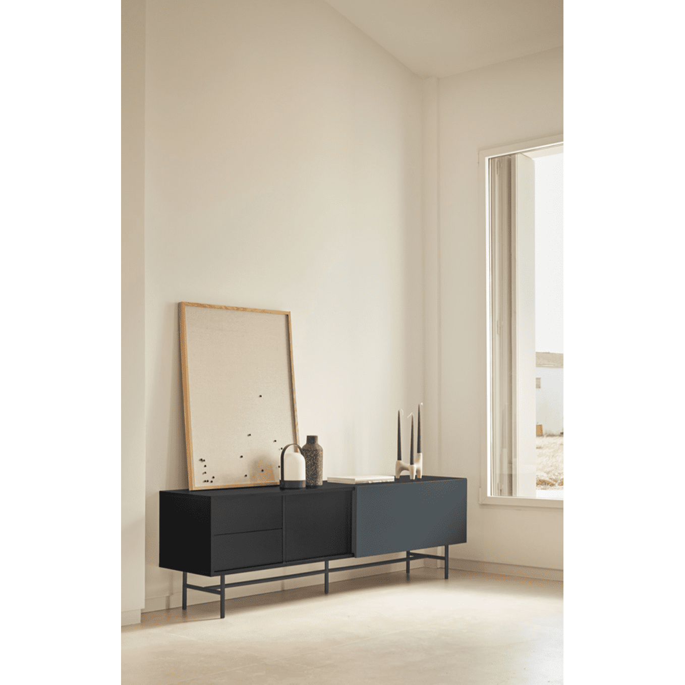 Una habitación minimalista moderna con una mesa Mueble TV Nube 2P2C, obras de arte abstractas y elementos decorativos cerca de una gran ventana, que presenta una personalización única en sus elementos de diseño.