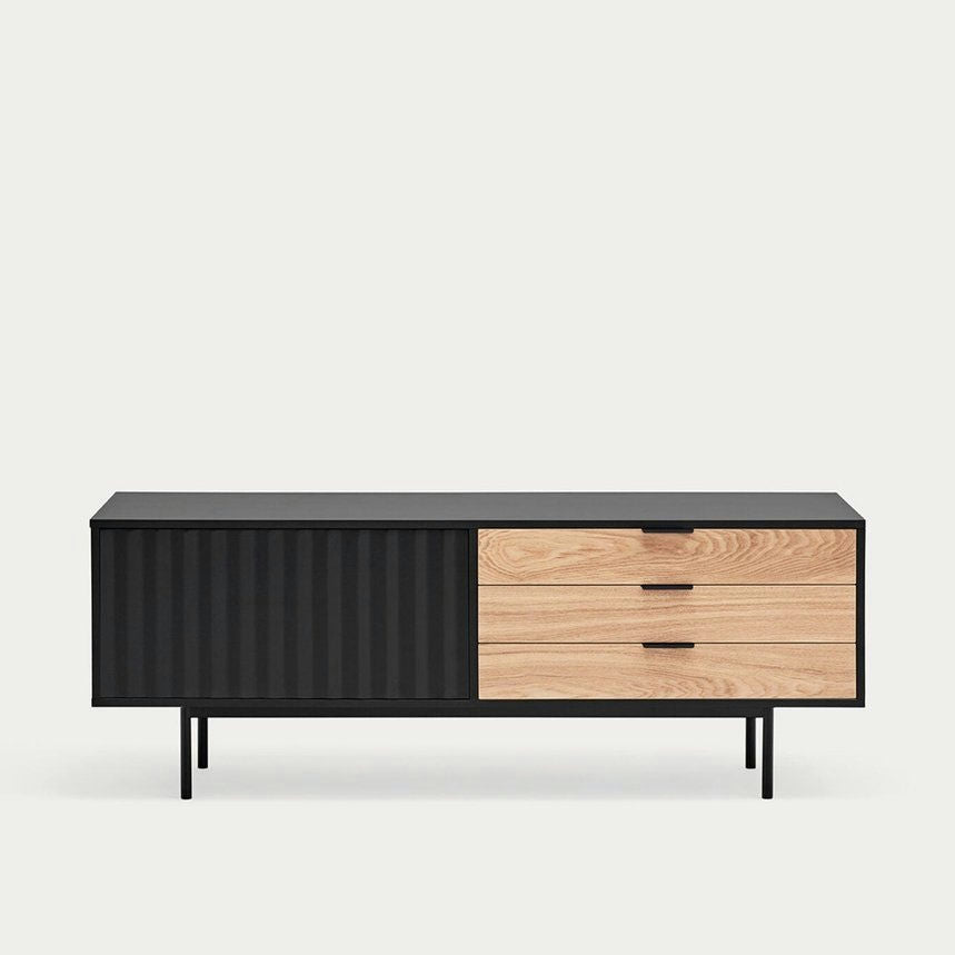El Mueble TV Sierra 1P3C cuenta con un aparador moderno con una puerta corrediza corrugada negra, tres cajones de madera y delgadas patas de metal negro, que ofrecen un almacenamiento elegante. Es ideal para quienes buscan un diseño asimétrico en su espacio de estar.