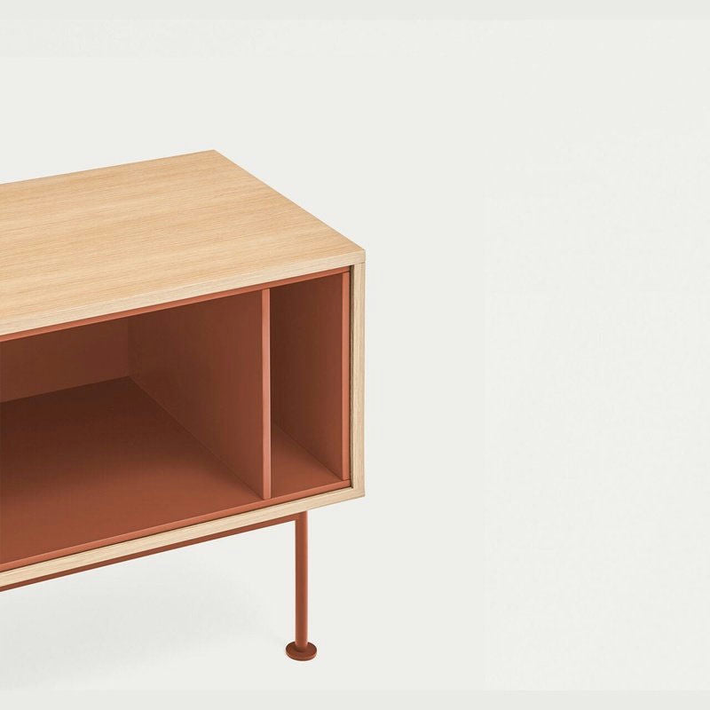 El mueble TV Yoko 1P2C presenta un diseño minimalista de madera, un panel de madera clara y una base de metal de color marrón anaranjado con una sección lateral abierta, ideal como una elegante pieza de almacenamiento o un mueble TV contemporáneo.