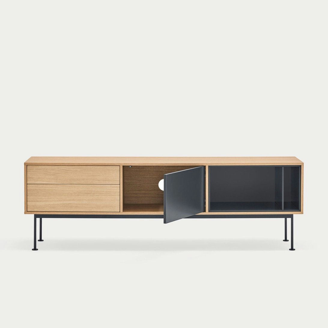 El Mueble TV Yoko 1P2C es una moderna pieza de madera con patas de metal negro, que cuenta con dos cajones y un mueble abierto con una puerta ligeramente entreabierta, mostrando un almacenamiento elegante.