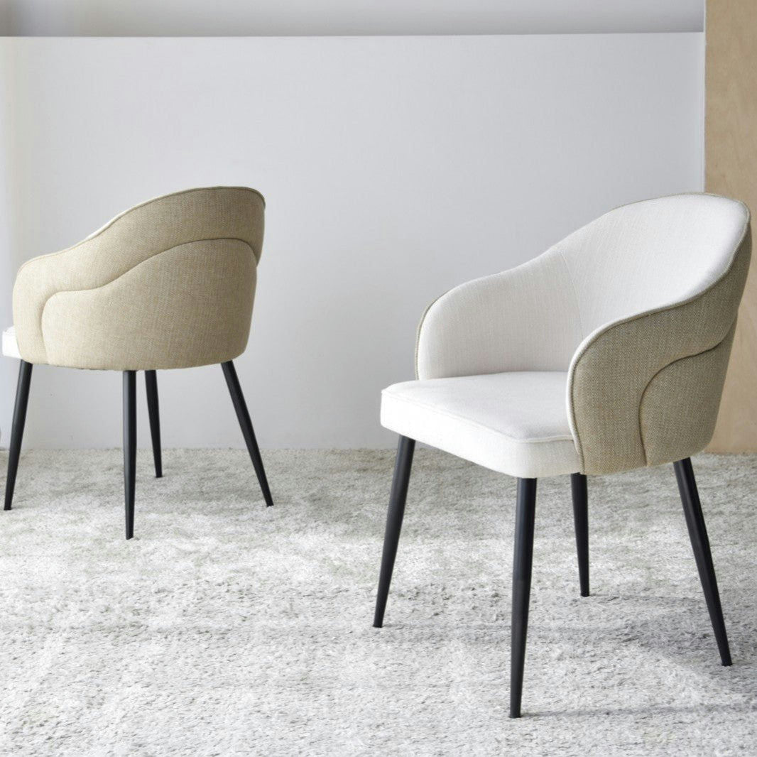 El Pack 2 Sillas de Comedor con Reposabrazos Roma en color beige presenta tapizado beige y elegantes patas metálicas, elegantemente colocadas sobre una alfombra gris claro.