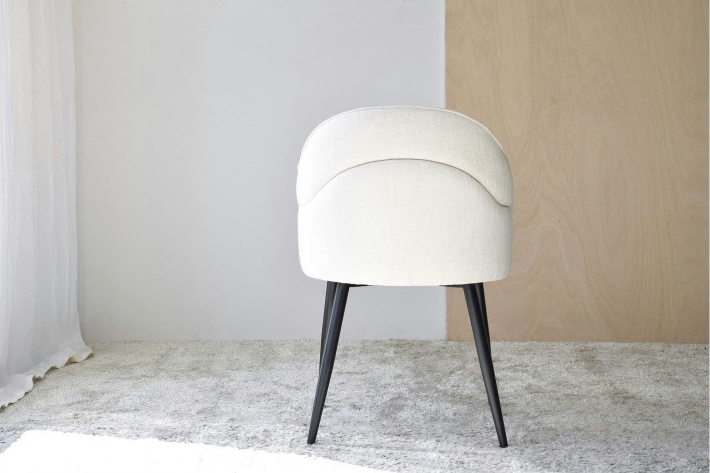 Un Pack de 2 Sillas de Comedor con Reposabrazos Roma (Beige claro) se asienta sobre una alfombra gris texturizada sobre un fondo de dos tonos de blanco y madera clara, irradiando estilo contemporáneo.