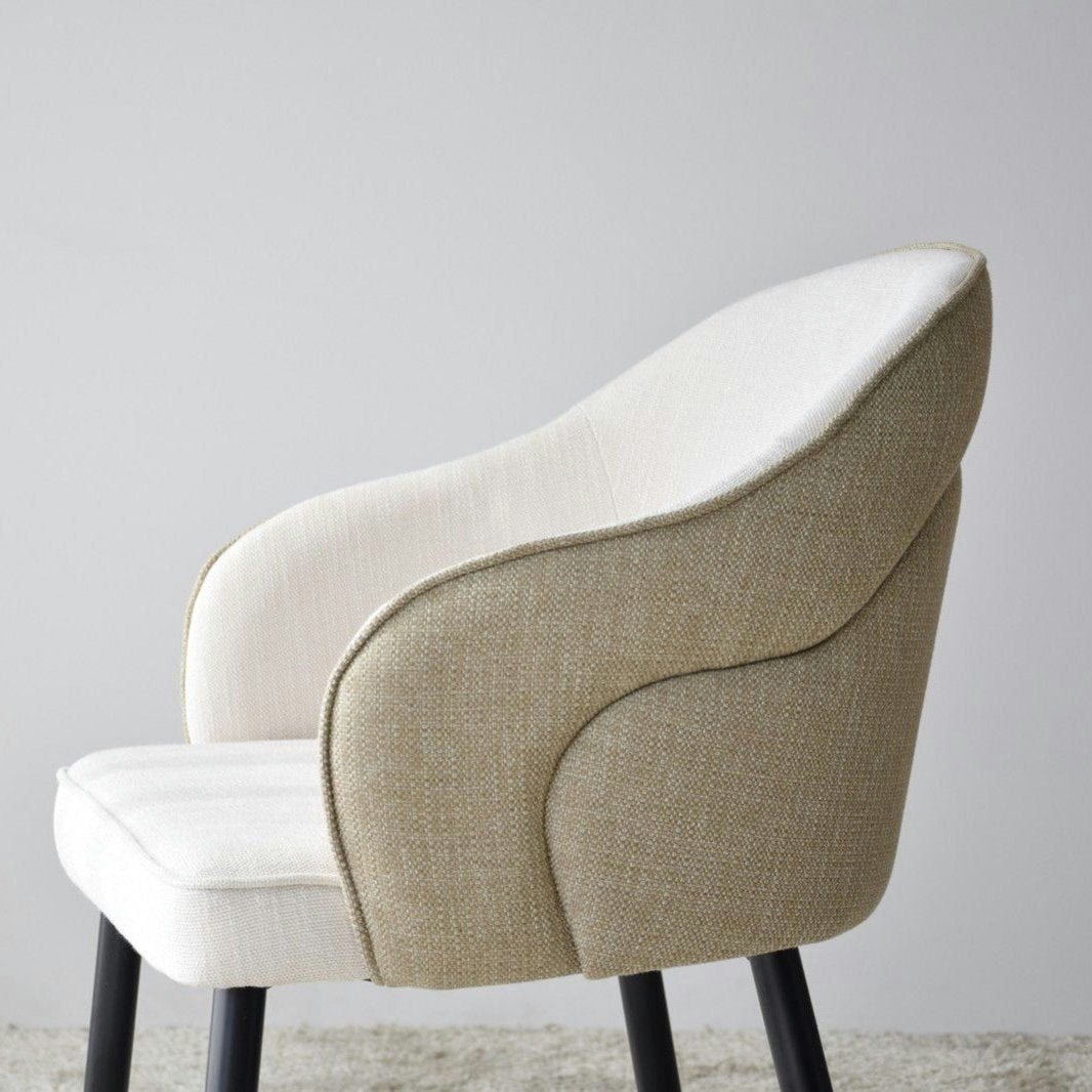 El Pack 2 Sillas de Comedor con Reposabrazos Roma en color beige presenta elegantes patas metálicas y se apoya con gracia sobre un piso alfombrado claro.