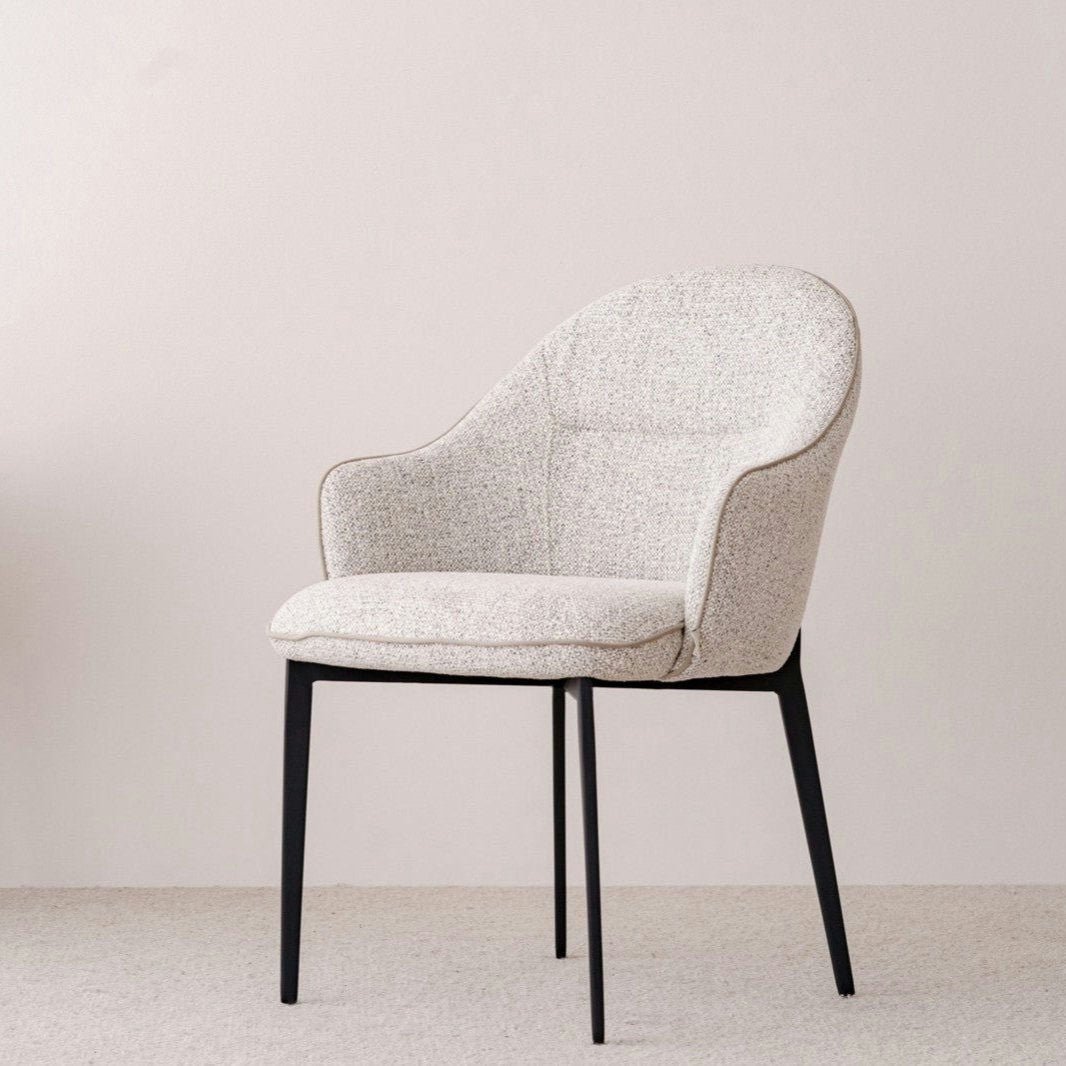 Explora el Pack 2 Sillas de comedor tapizadas Beige y Gris Elna, que presenta un diseño moderno con respaldos y apoyabrazos curvos. Estas sillas están tapizadas en tela texturizada y se apoyan sobre delgadas patas de metal negro, ofreciendo un toque de estilo contemporáneo sobre un fondo de color claro.