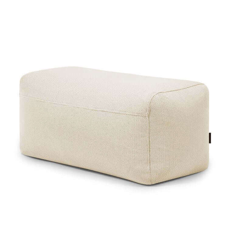 El Pouf Plus 100 Canaria es un puf rectangular de tela beige con bordes redondeados para uso exterior, ideal como puf ergonómico o asiento de jardín, mostrado sobre fondo blanco.