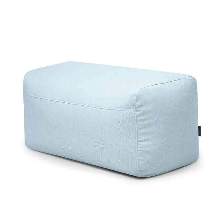 El Pouf Plus 100 Riviera es una otomana rectangular de color azul claro diseñada para su uso en exteriores, con bordes lisos y estilo minimalista para ofrecer un asiento adicional, mostrada sobre un fondo blanco liso.