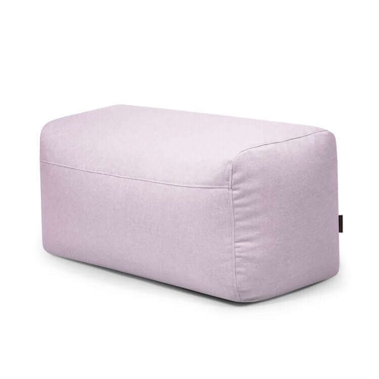 El Pouf Plus 100 Riviera, un puf rectangular de color morado claro con suaves bordes redondeados, es ideal como práctico reposapiés versátil o asiento adicional para exteriores, mostrado sobre un fondo blanco liso.