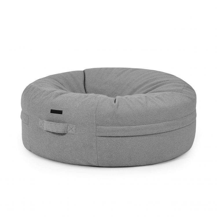 El Puff gigante redondo de tejido borreguito ROLL 135 TEDDY (135×135×50 cm) ofrece estilo moderno y comodidad a tu salón, con borde acolchado y asa lateral, en diseño gris mostrado sobre fondo blanco.