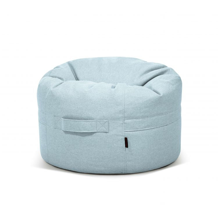 Puff redondo ROLL 80 RIVIERA azul claro (80×80×35 cm) de tejido antimanchas e hidrófugo, con asa lateral; versátil para uso en interiores y exteriores. Sobre fondo blanco liso. Funda extraíble para facilitar la limpieza.