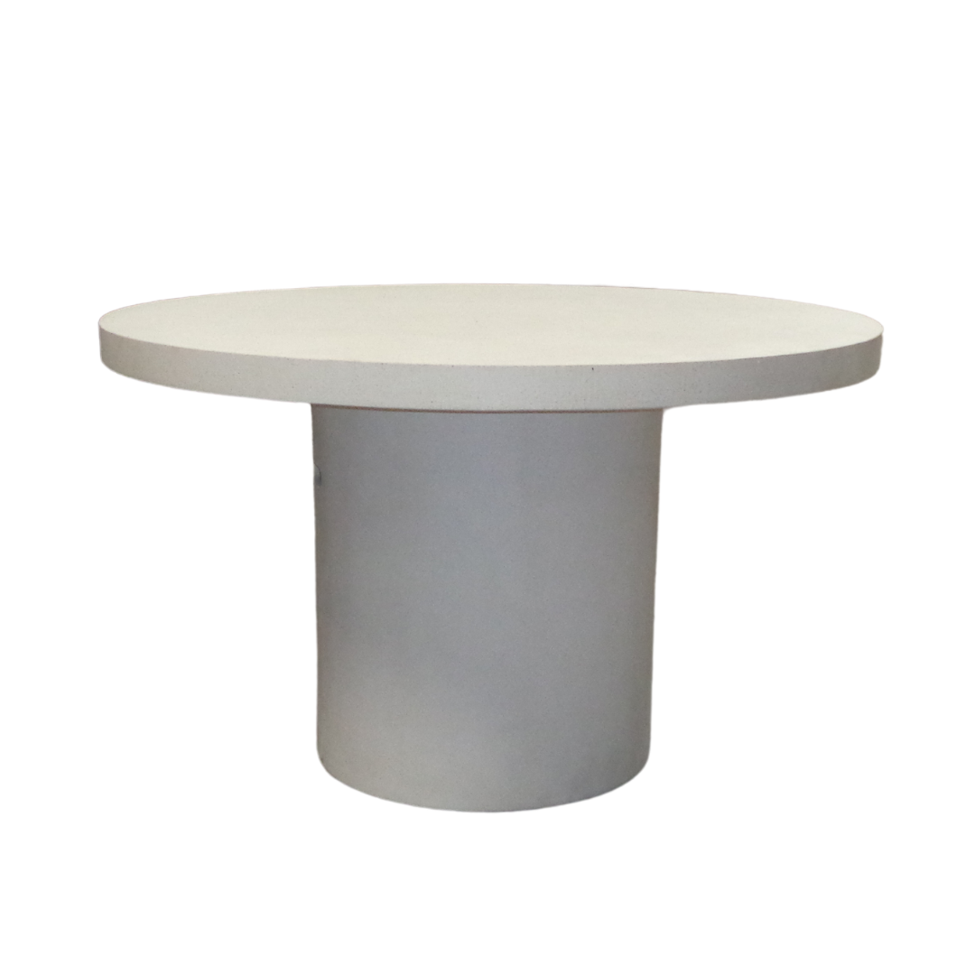 Una mesa de comedor redonda y blanca, la Mesa de comedor redonda (Ø130 cm) Topi, presenta una base cilíndrica en cemento blanco sobre un fondo blanco, mostrando un diseño moderno.