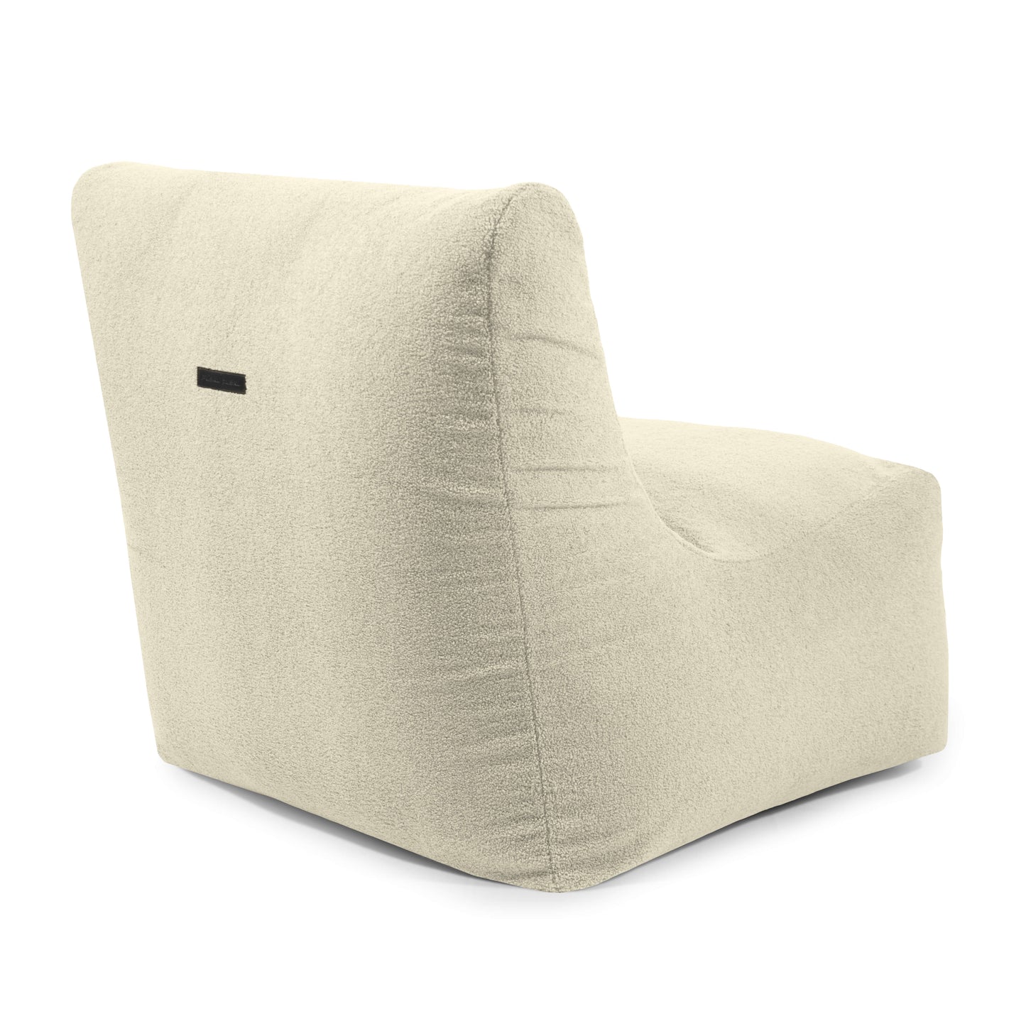 El Bean Bag Seat 100 Teddy es un sillón moderno, sin brazos, tapizado en beige claro, con respaldo ligeramente reclinado y una etiqueta rectangular negra cerca de la parte superior, que ofrece comodidad ergonómica para relajarse con estilo.
