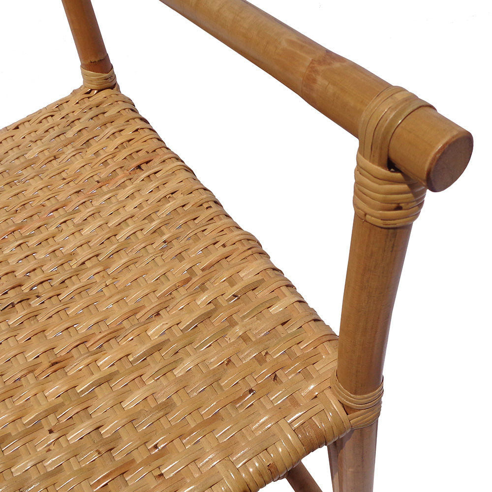 Primer plano de la silla de comedor de bambú y ratán Sagitario, que cuenta con una estructura de madera y un asiento y apoyabrazos de ratán tejido. El intrincado patrón de tejido y el acabado suave muestran la artesanía tradicional, mientras que su diseño versátil combina a la perfección con cualquier decoración.